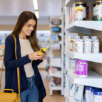 Happy Latin American woman buying nutritional supplements at the pharmacy and reading the label on the bottle